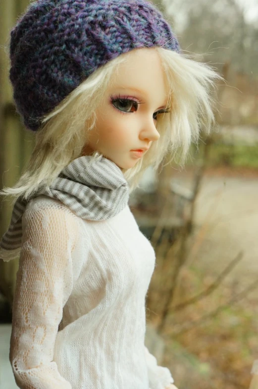 a white female doll wearing a knitted hat and scarf