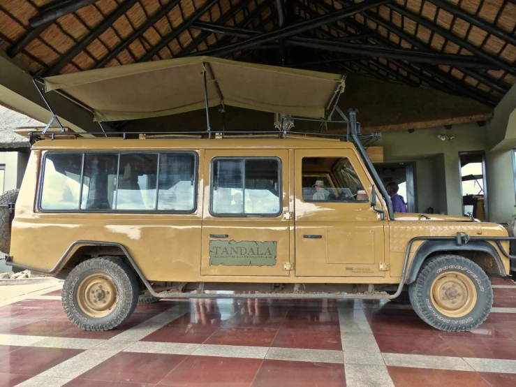the big yellow jeep is parked under the shelter