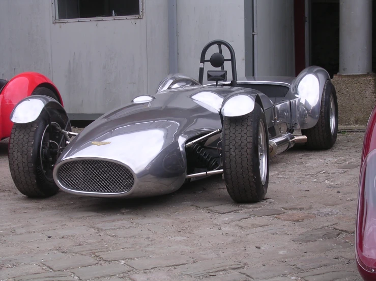 a metal car on the ground, with wheels out front