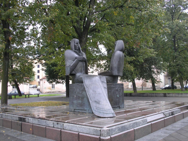 a statue of two men in the park with a skateboard on it