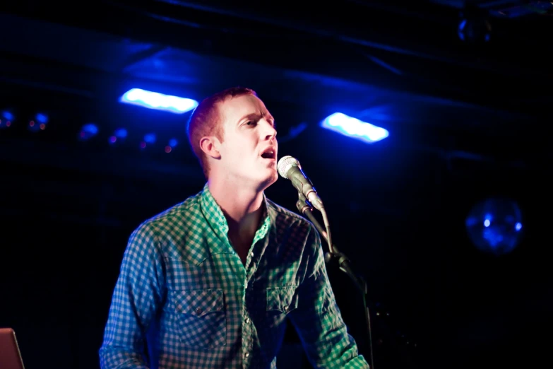 a man in plaid shirt singing into a microphone