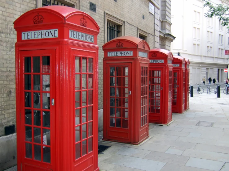 a row of red telephone booths lined up on the side of a building