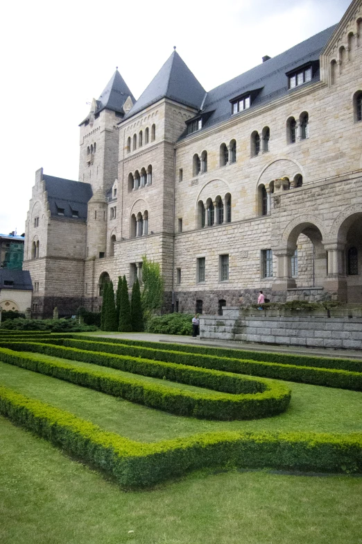 a stone building with a lot of green bushes next to it