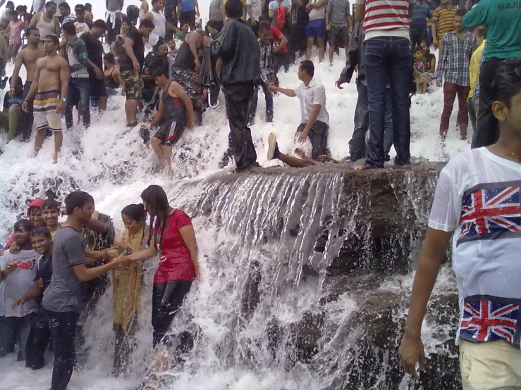 several people standing by an opened fire hydrant with water running