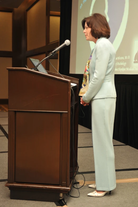 a woman stands in front of a podium while giving a speech