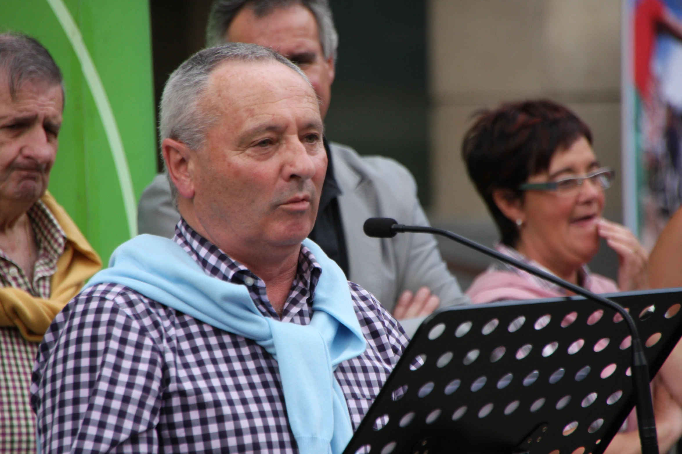 people standing in front of a podium while one man holds a microphone