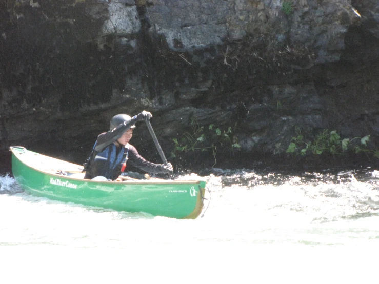 a man riding on the back of a green canoe