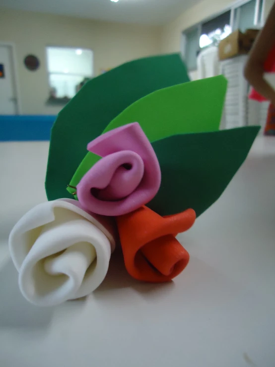 some different colored paper flowers on a white table