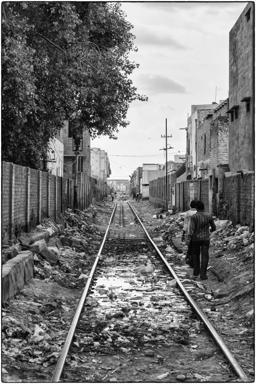 black and white pograph of boy walking down train tracks