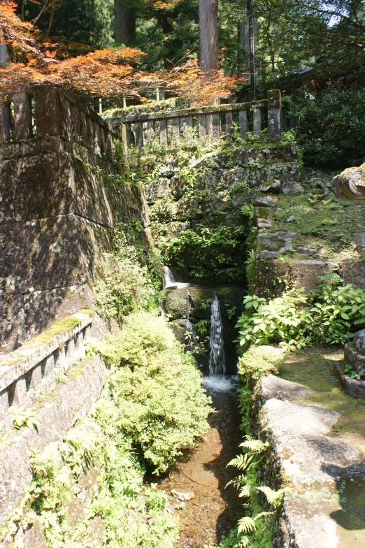 a stream is near a fence and a stone bridge