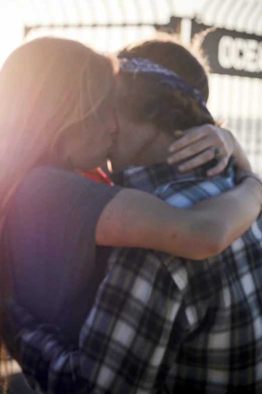 a man and woman are kissing in front of fence