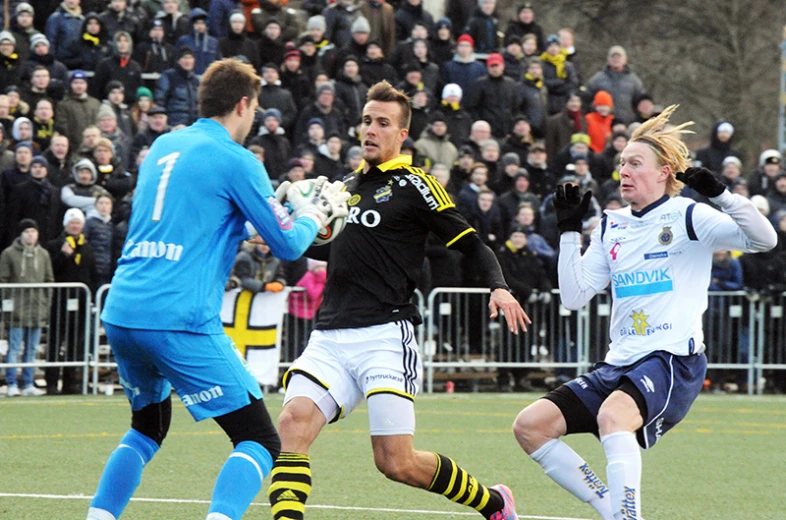 two soccer players trying to block the ball from going by another player