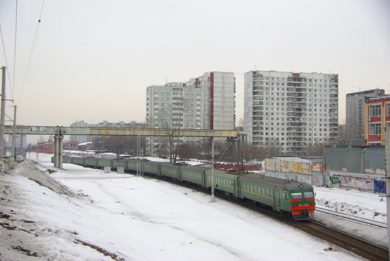 a train traveling past tall apartment buildings on the side of the street