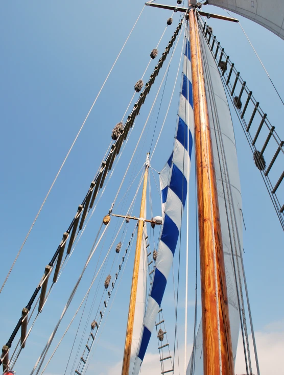 a tall ship with ropes and blue sails