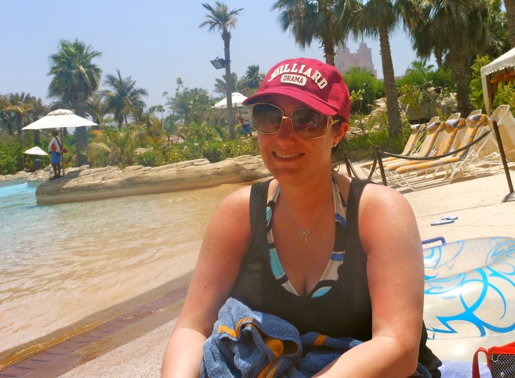 a woman with sunglasses and a hat sits on a beach