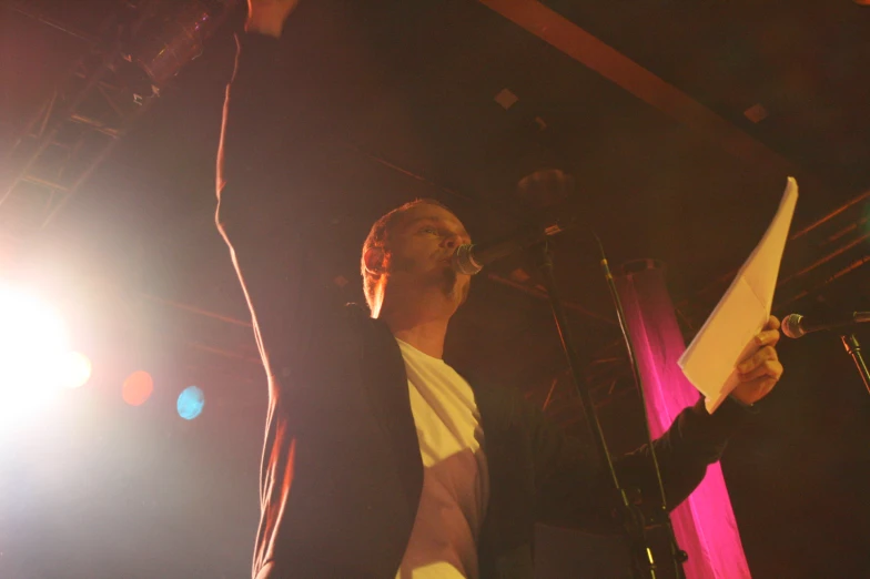 a man standing with a microphone next to a sheet of paper