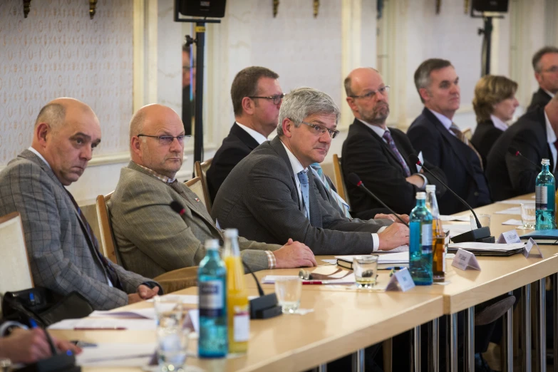 men sitting at a long table with bottles of water