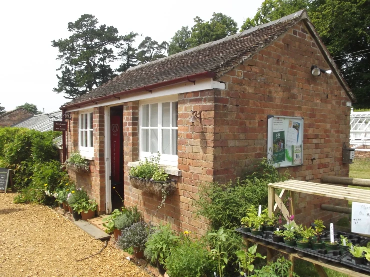 a garden filled with plants sitting next to a red brick building