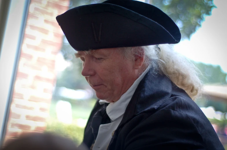 an old man with white hair wearing a black hat