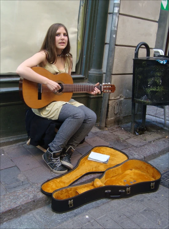 a woman sits with her guitar and instrument outside