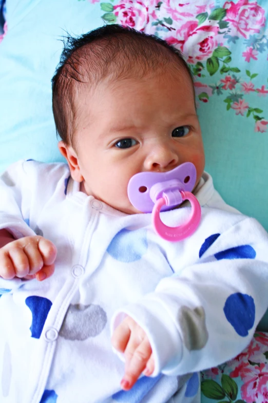 a baby holding up a pacifier in its mouth