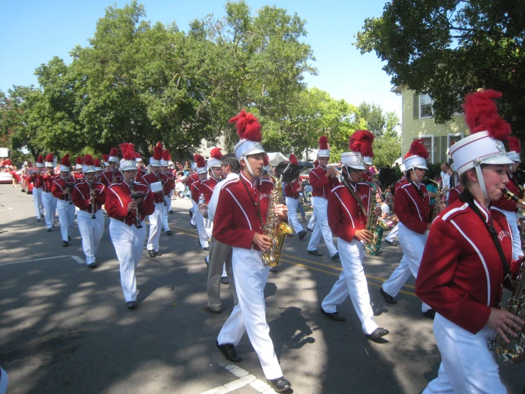 a band is in a parade that is wearing red and white outfits