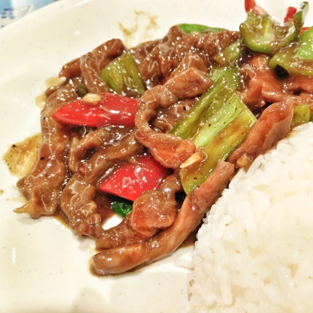 food with beef and vegetables sitting on top of rice