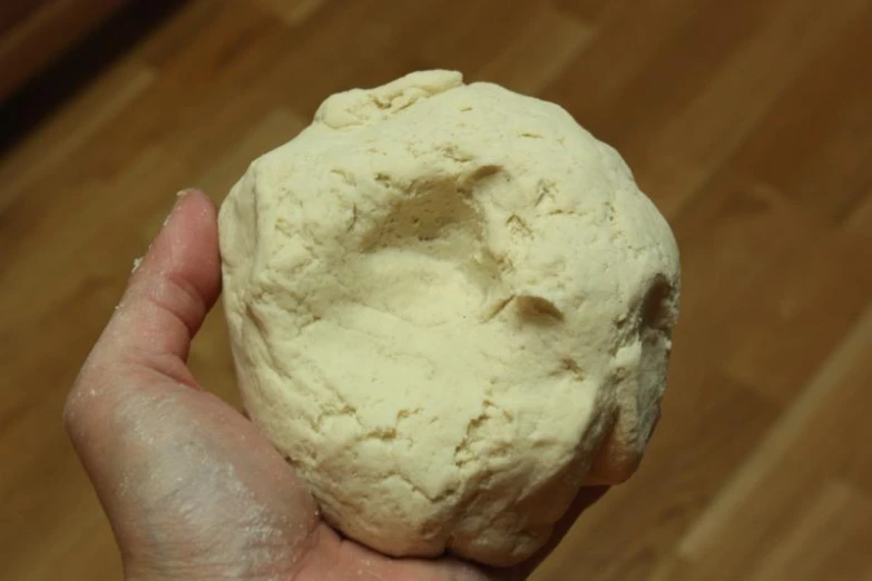 a person holding a white dough ball in their hand