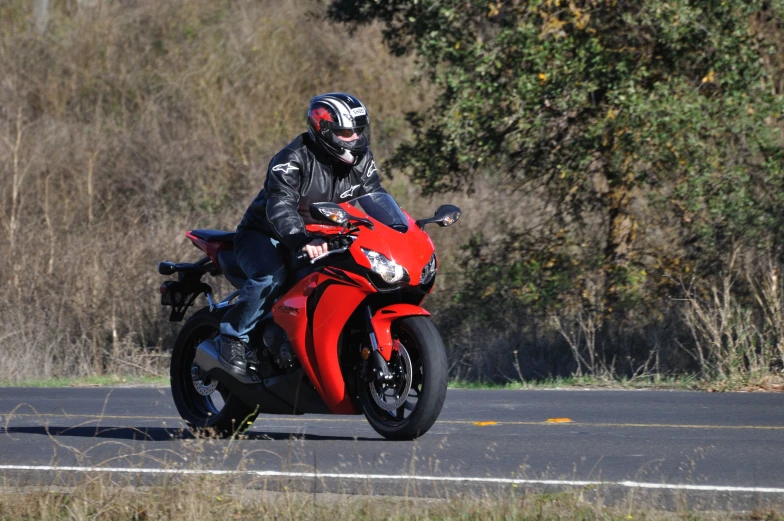 a motorcycle rider in a helmet is riding a red motorcycle