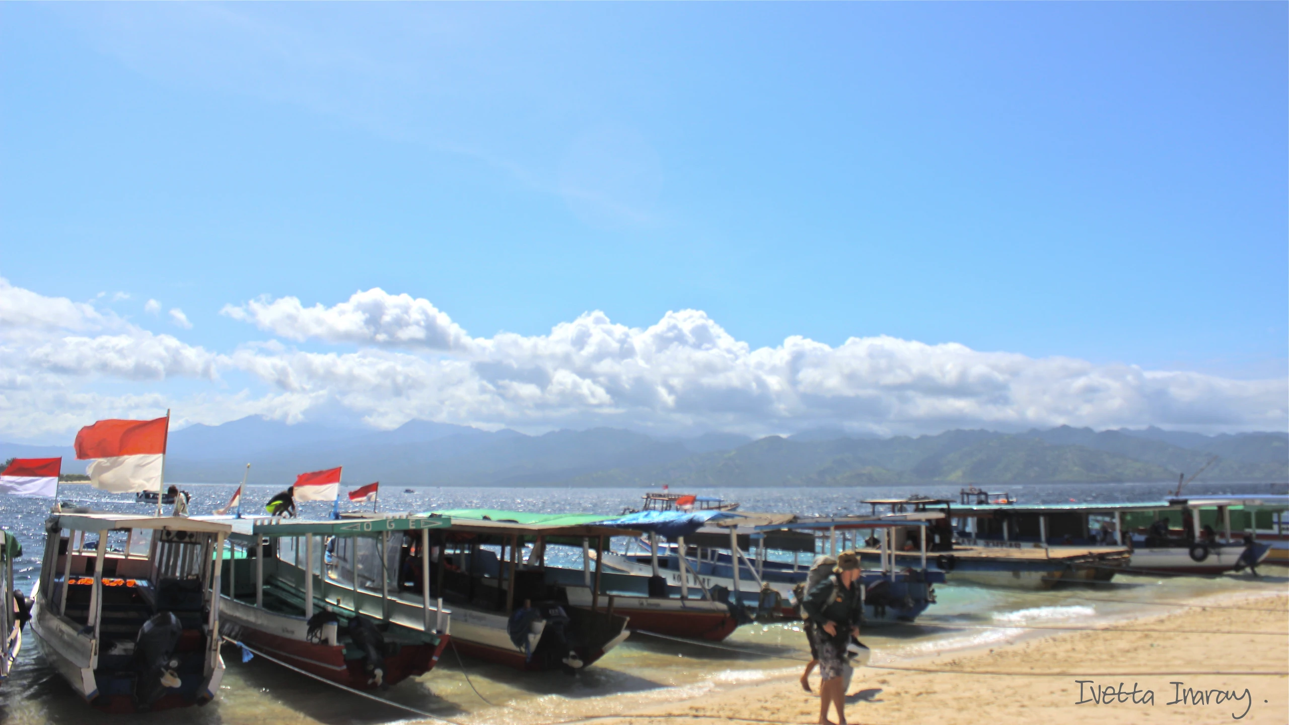 people are walking on the beach by several boats