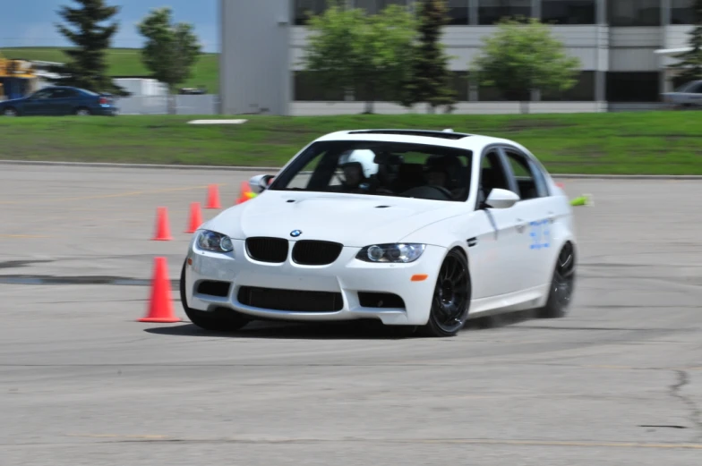 a white car is driving around some cones