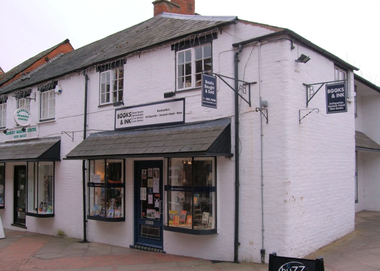 the outside of a white brick building has several small shops