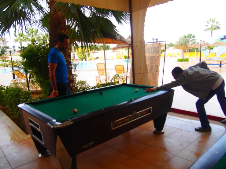 two people playing pool on the inside of a building