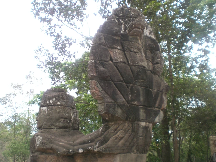 a statue of a sitting person is under a tree