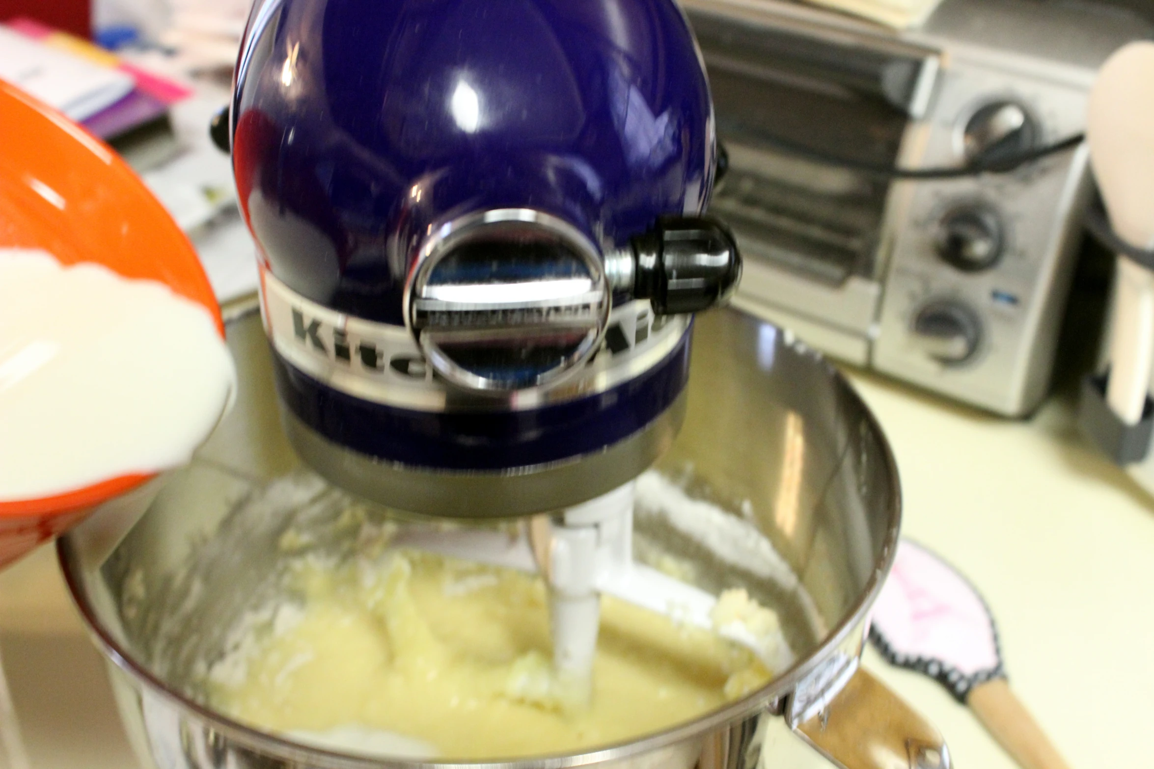 a purple mixer mixing white cream on the counter