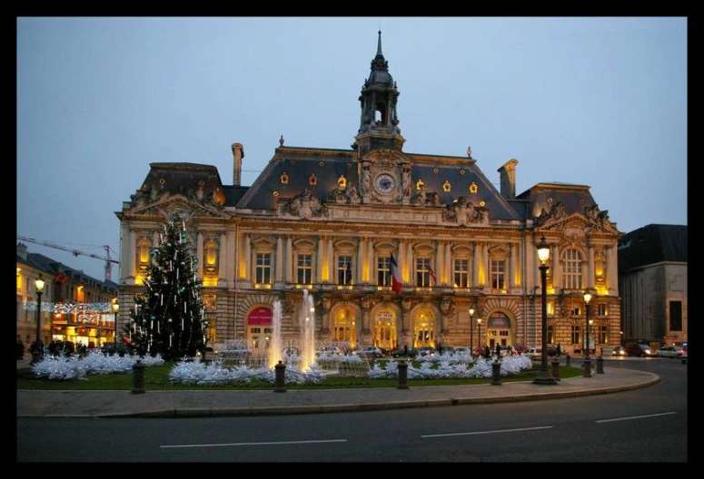 large gold colored building with christmas trees and lights around it