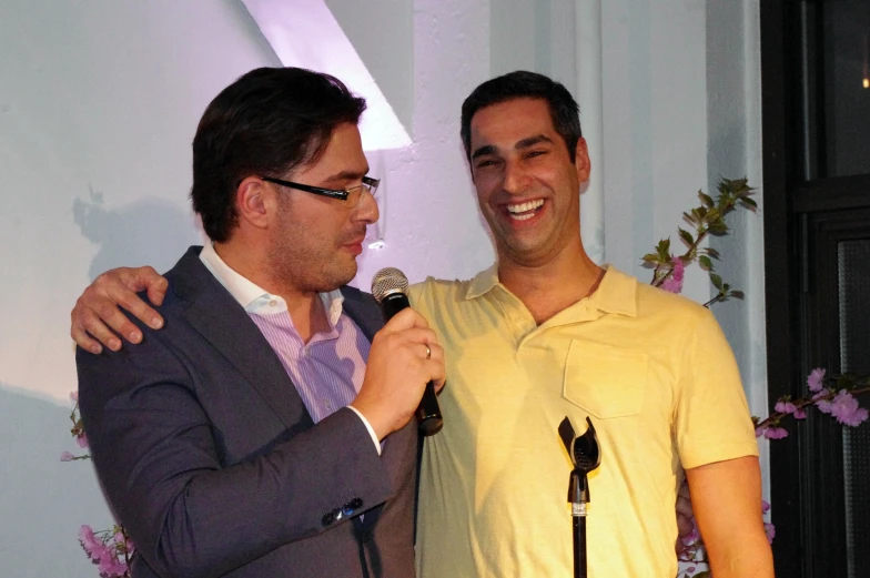 two men are sharing a microphone with each other