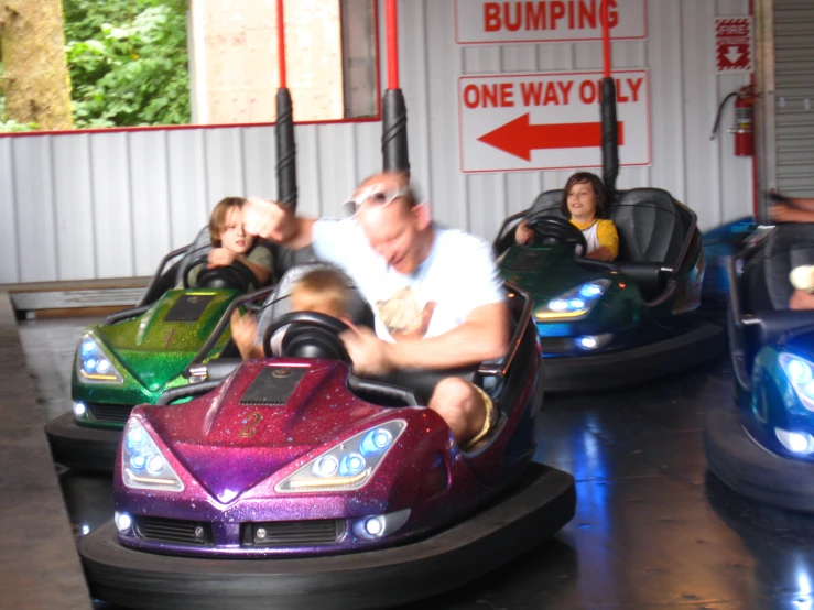 a man riding a bumper car with a child in his lap