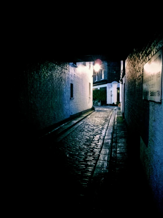 a narrow street at night with a person sitting in the middle
