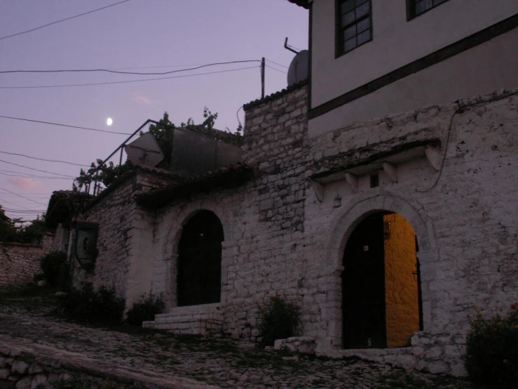 the moon is seen above a building next to a cobblestone walkway