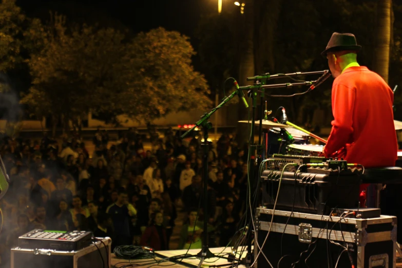 man in an orange jacket with a hat on top playing an electronic equipment