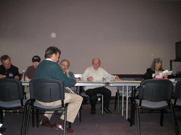 several people are sitting at a table with papers