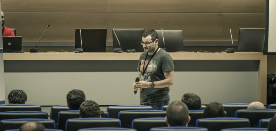 man in black shirt standing up in front of a large audience