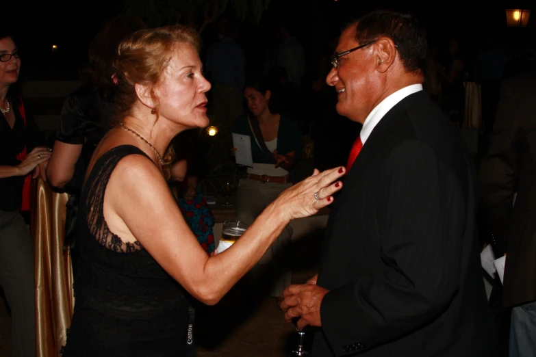 an old man is holding onto the hand of an older woman at a formal function