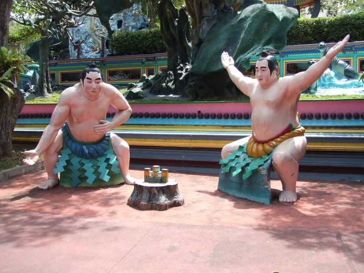 a couple of sumo wrestlers siting on benches