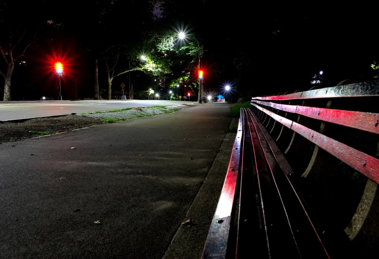 a park bench is by a street at night
