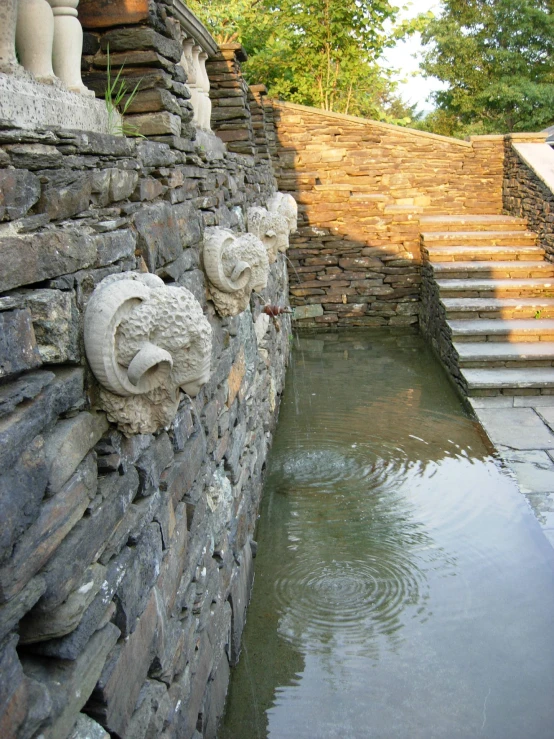 stone sculptures and water inside a stone walled garden