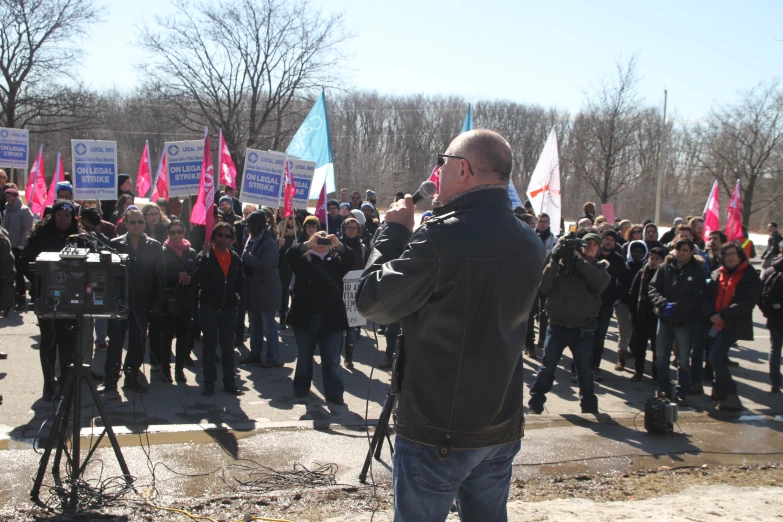 a man standing in front of a crowd of people holding pink flags