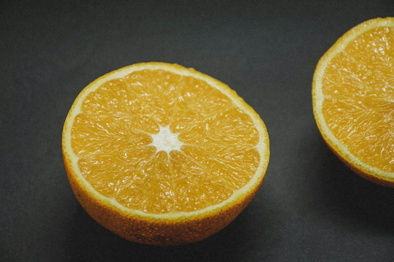 two halves of an orange on a black surface, by Carey Morris, pexels contest winner, stopmotion animation, medium format, on grey background, over-the-shoulder shot