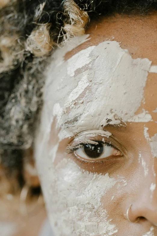 a close up of a person with white paint on their face, trending on pexels, renaissance, natural complexion, hair over face, covered, looking at you